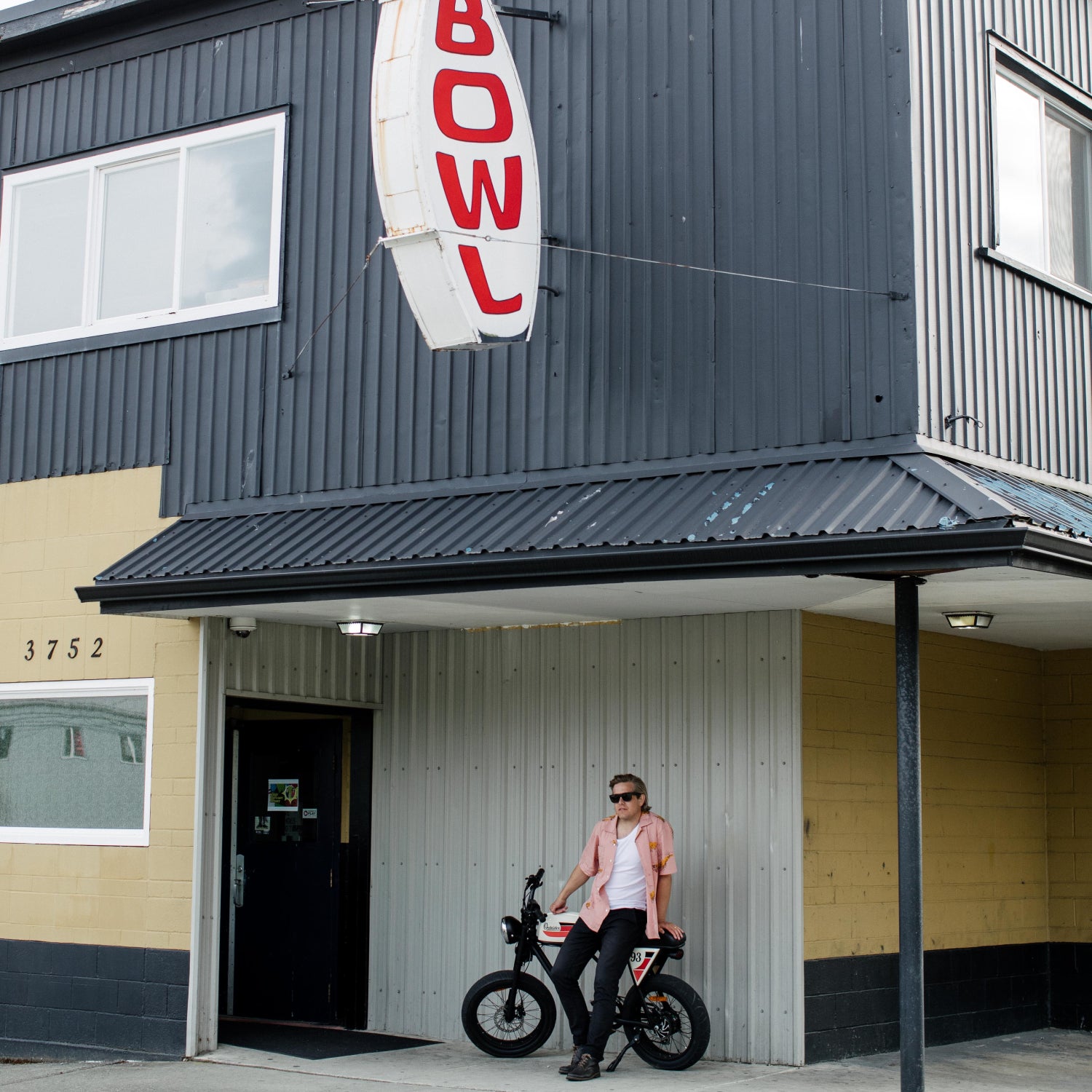 man in front of bowling alley with vintage electric bike