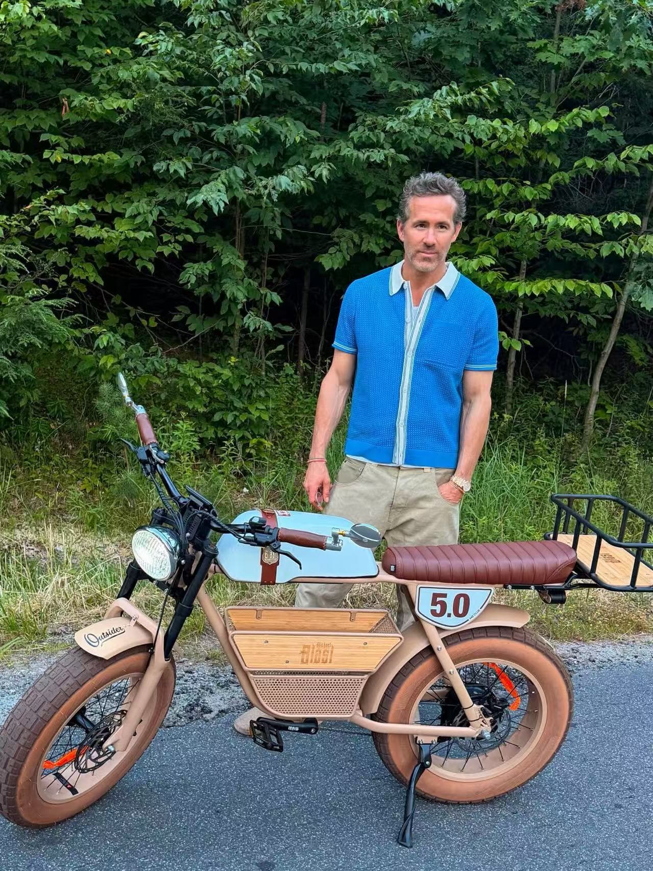 Ryan Reynolds standing behind his sand Outsider 5.0 with mid basket, mirrors and rear rack